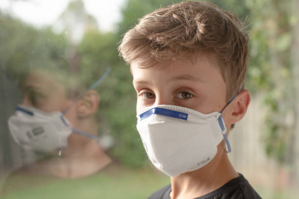 istock Boy in mask at window 1215232356