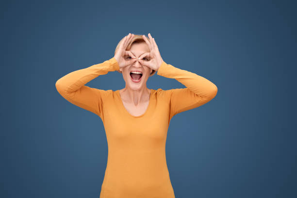 istock Middle aged woman rejoice, making binoculars gesture 1215236951