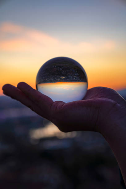 istock woman's hand with crystal ball Sunset 1215239008