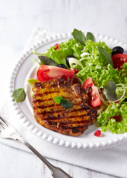 istock Grilled pork steak with fresh salad. White wooden background. Copy space. 1215241665