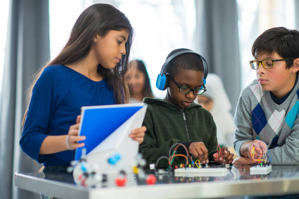 Elementary School Students Learning About Circuits stock photo A group of multi-ethnic elementary school students  learn about circuits.  They are using two small circuit boards and wires. teacher classroom child education stock pictures, royalty-free photos & images