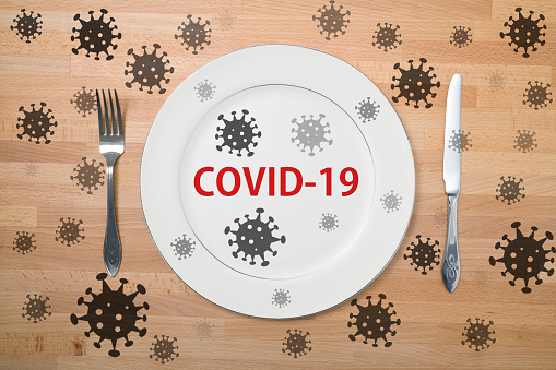 White plate with fork and knife on the table during quarantine. Coronavirus.