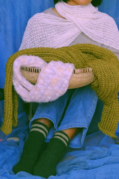 Concept with woman wear blue jeans, white woolen sweater, sock, white and moss green wool scarf on blue background, knitted handmade product to make warm for winter as hobby in free time