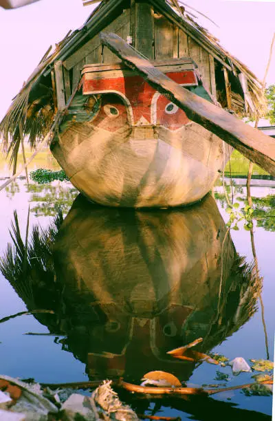 HO CHI MINH CITY, VIET NAM- JAN 15, 2020: Amazing wooden boat with dried leaves roof mooring at river, close up boat eyes looking straight, the boat reflect on water make impression art, Vietnam.