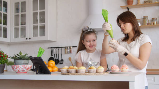 istock Mother and daughter icing cupcakes 1215258684