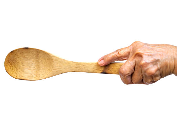 senior woman's left hand holding wooden ladle on white background, close up shot, selective focus, kitchen utensils concept - copy space left imagens e fotografias de stock