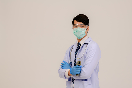 Doctor wearing protective surgical mask ready to use infrared forehead thermometer (thermometer gun) to check body temperature for virus symptoms - epidemic virus outbreak concept