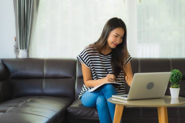 istock Portrait beautiful young asian woman using laptop or computer noterbook on sofa with concept work from home 1215269543