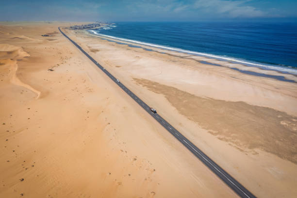 Walvis Bay Namibia Swakopmund Endless National Road Aerial View Swakopmund Langstrand Aerial Drone Point of view along the dry Sea and Sand Langstrand Beach Coast between the cities of Swakopmund and Walvis Bay. South Atlantic Ocean Coast of Namibia at Swakopmund. Long, straight National Road B2 with driving Trucks and Cars. Swakopmund - Walvis Bay, Erongo Region, Namibia, Africa. swakopmund photos stock pictures, royalty-free photos & images