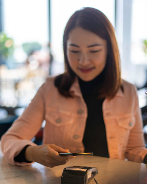 istock Young Asian woman making payment using mobile phone. 1215271747