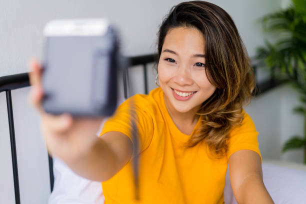 istock Young Asian woman is taking selfie using her polaroid camera. 1215271838