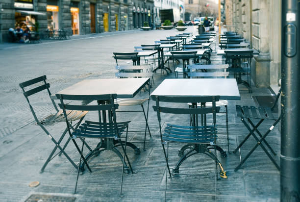 Empty  terrace with tables and chairs in wood and metal at coffee and resteurant beside sidewalk in center city. Environment city life during confinement due to corona virus or covid-19  Background business dramatic scene conept. stock photo