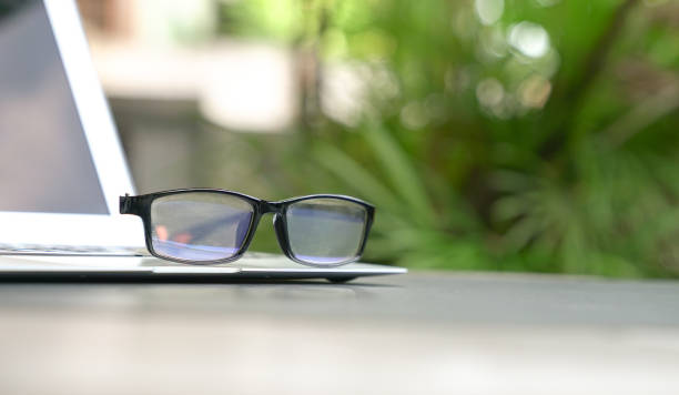 istock Spectacles on top of computer laptop with green nature background. 1215277486