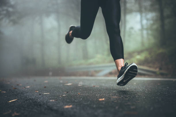 istock Unrecognizable athlete jogging on the road during rainy day. 1215279818