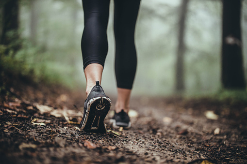 Close up of unrecognizable athlete walking on muddy path during autumn day. Copy space.