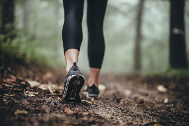 feche acima de atleta irreconhecível andando em caminho lamacento. - walking shoe human foot footpath - fotografias e filmes do acervo