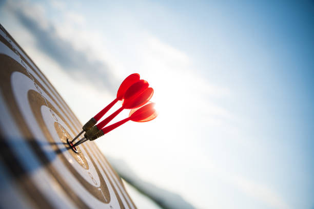 Close up shot red darts arrows in the target center on dark blue sky background. Business target or goal success and winner concept. Close up shot red darts arrows in the target center on dark blue sky background. Business target or goal success and winner concept. business target photos stock pictures, royalty-free photos & images