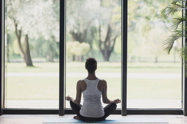 istock Young woman meditating and practicing yoga at home 1215285764