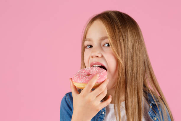 istock girl playing with a donut on a pink background 1215289807