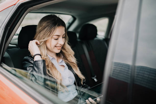 istock Smiling woman sitting in a car with tablet computer 1215292067