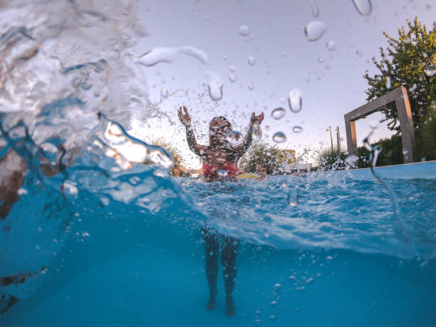 istock Young woman splashing camera in pool 1215292103