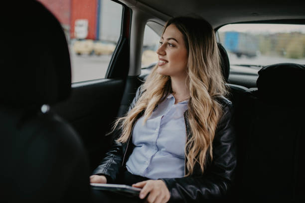 istock Smiling woman sitting in a car with tablet computer 1215292128