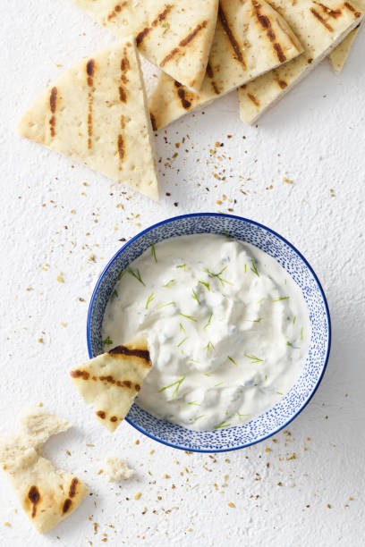 Tzatziki dip and pita bread chips Tzatziki dip and grilled pita bread chips with seasoning on a wooden cutting board dipping stock pictures, royalty-free photos & images
