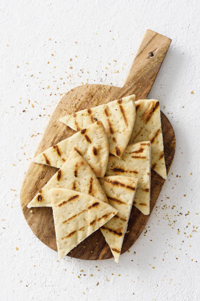 Grilled pita bread Grilled greek pita bread chips with seasoning on a wooden cutting board pita bread stock pictures, royalty-free photos & images
