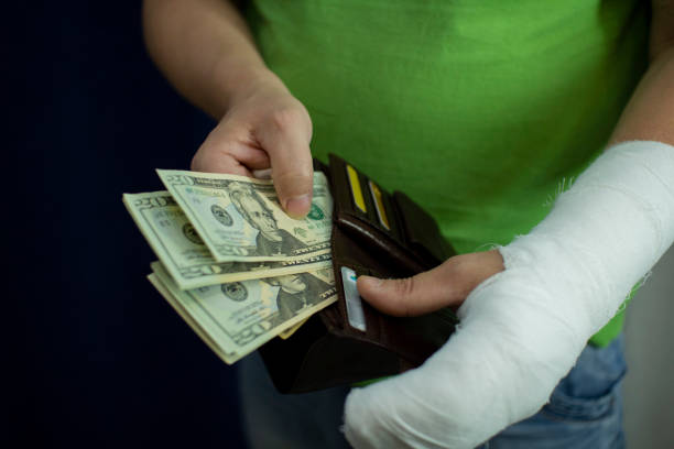 A man with an arm in a cast counted out money from the cost and expenses of emergency medical care at the hospital . stock photo
