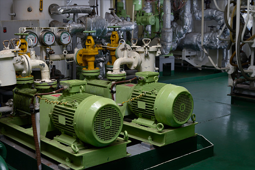 Engine room interior of a big ocean going ship with electrical motors, piping, gauges, valves etc.