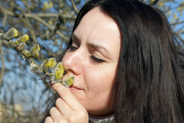 A girl walks through the spring park. Examines a flowering willow.