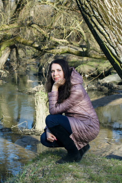 istock Girl in a spring park. Squatting by the river. 1215310507