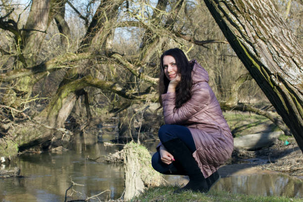 istock Girl in a spring park. Squatting by the river. 1215310522