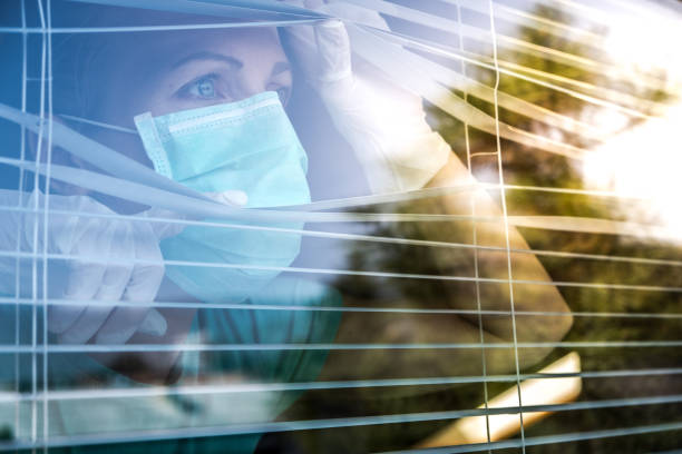 trabajador de atención médica preocupado mirando a través de una ventana - isolated despair hope assistance fotografías e imágenes de stock