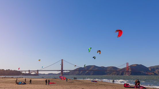 San Francisco - California, USA. October 27, 2019: Beautiful view of San Francisco Crissy Field beach with the kitesurfers in the sea on the backplan famous Golden Gate Bridge.