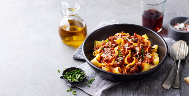 istock Pasta pappardelle with beef ragout sauce in black bowl. Grey background. Copy space. 1215312584