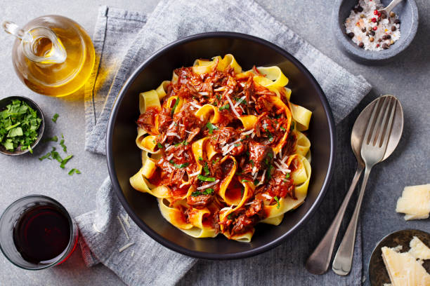 fettuccine de pâtes avec sauce ragoût de bœuf dans un bol noir. fond gris. fermez-vous vers le haut. vue du haut. - noodles photos et images de collection