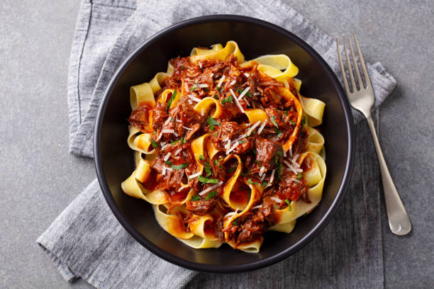istock Pasta pappardelle with beef ragout sauce in black bowl. Grey background. Top view. 1215312837