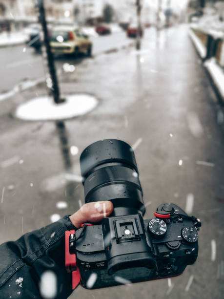 Unrecognizable person holding a DSLR camera on a snowy day.