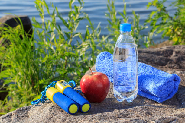 istock Jump rope, apple, towel and bottle with water on rock 1215314314