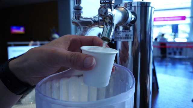 Pouring craft beer from cooler  into take away cup