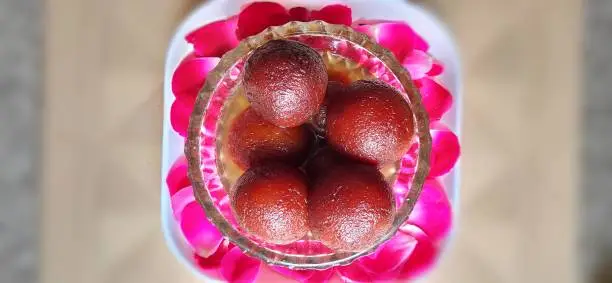 Photo of Indian recepe sweet gulabjamun with blurred background and simple decoration. Gulabjamun in a glass bowl.