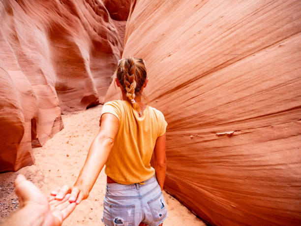 Couple holding hands inside slot canyon in Arizona, USA Follow me concept woman leading boyfriend inside slot canyon in USA, red rock sandstone page arizona stock pictures, royalty-free photos & images