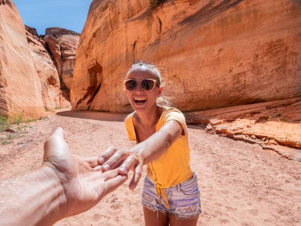 Couple holding hands inside canyon in Arizona, USA Follow me concept woman leading boyfriend inside slot canyon in USA, red rock sandstone page arizona stock pictures, royalty-free photos & images