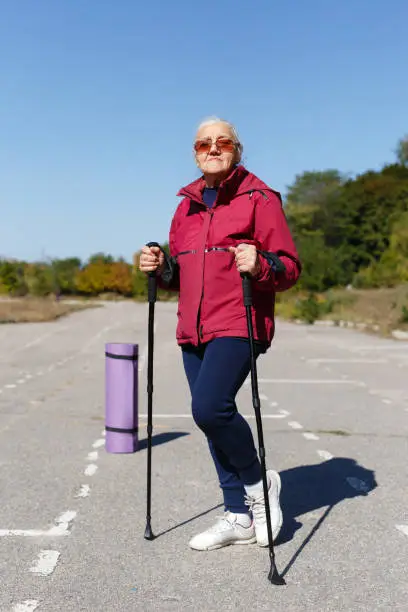 Portrait of a woman in sportswear and sunglasses. A woman runs in the stadium. Grandmother leads a healthy lifestyle. Happy grandmother goes in for sports.