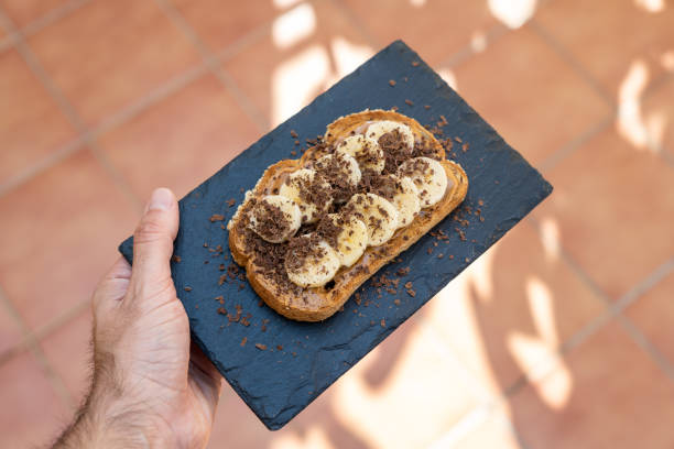 istock Crispy cereal toast with peanut butter, bananas and chocolate on a hand 1215318836