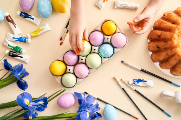 bambina che tocca oggetti pasquali sul tavolo - easter easter egg paintbrush holding foto e immagini stock