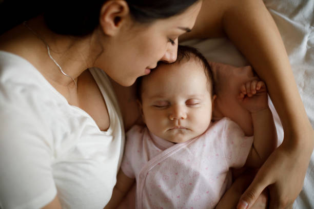 아름다운 젊은 어머니와 그녀의 귀여운 작은 아기는 집에서 침대에서 자고 - mother new baby nursery 뉴스 사진 이미지