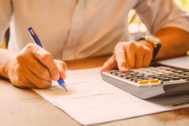 istock Businessman holding pen on document to analyzing accounting with calculator. 1215320130