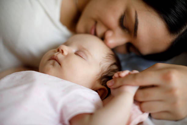istock Mother and baby sleeping together at home 1215320389